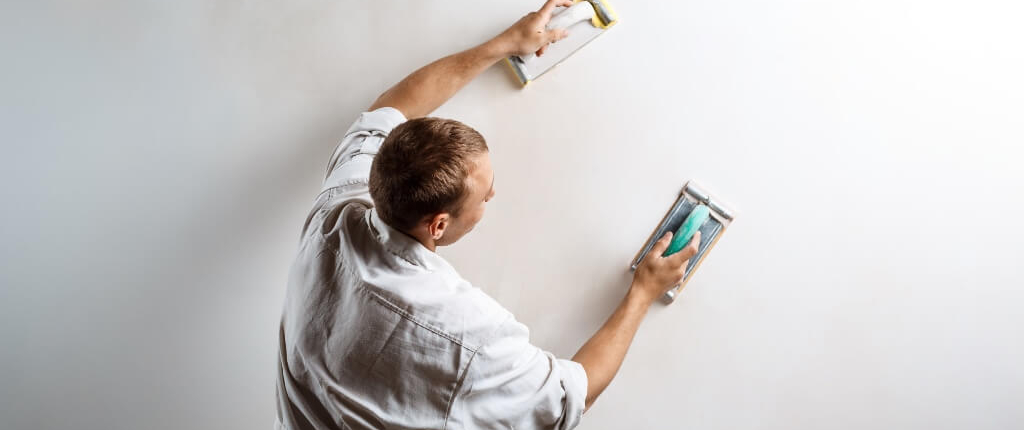Image by cookie_studio on Freepik Plasterer sanding a wall