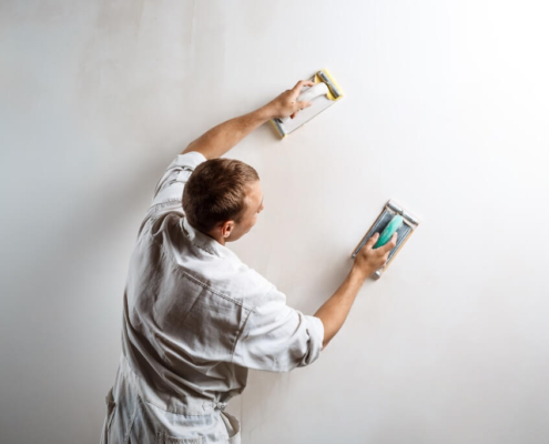 Plasterer sanding a wall