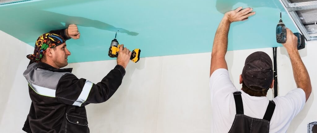 Image by ededchechine on Freepik Two men drilling plasterboard into an unfinished ceiling